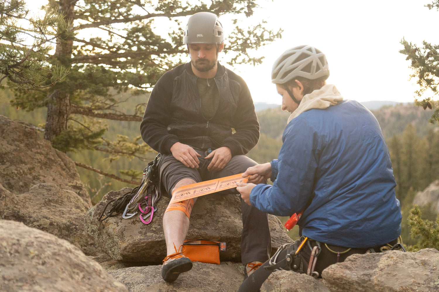 A man applying the first aid kit tourniquet to another persons injured leg