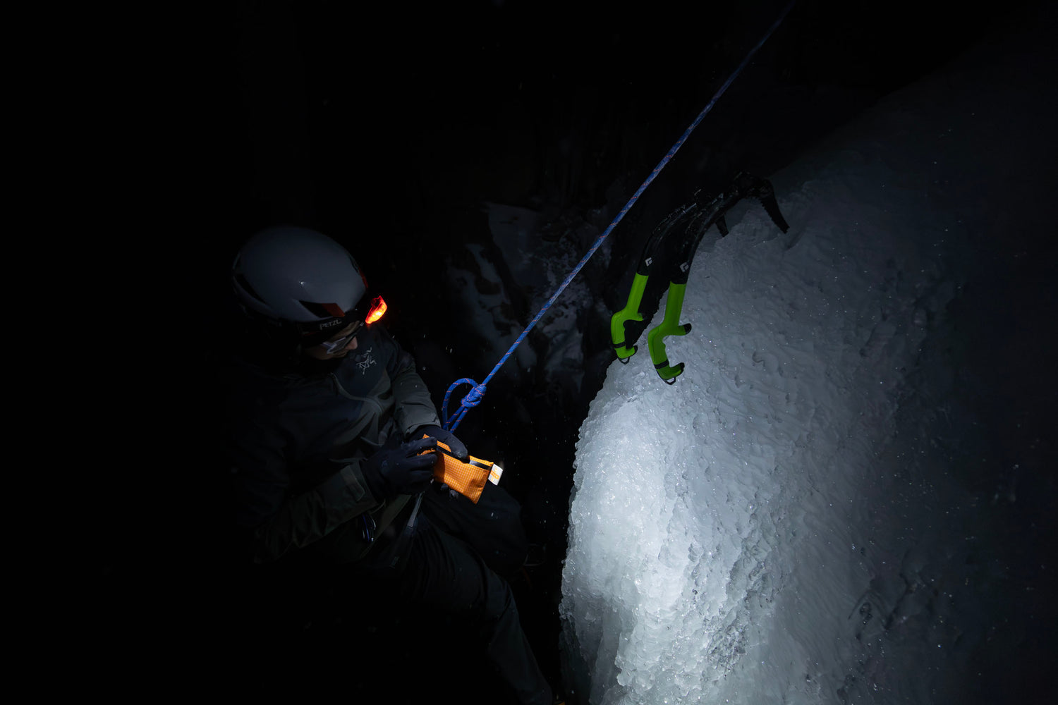 An ice climber opening a Peak First Aid First Aid kit in the dark illuminated by head lamp mountaineering